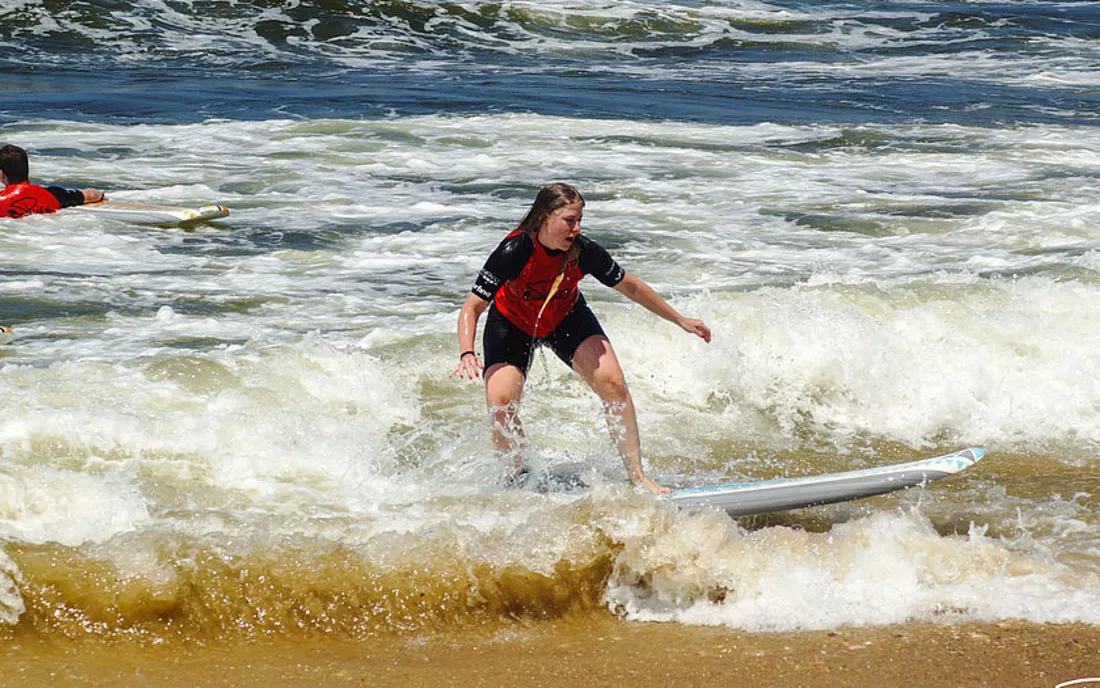 Surferin beim Surfen lernen im Shorebreak