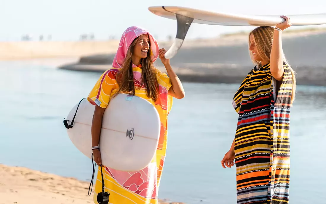 Surferinnen im Surf Poncho und mit Surfbrett am Strand