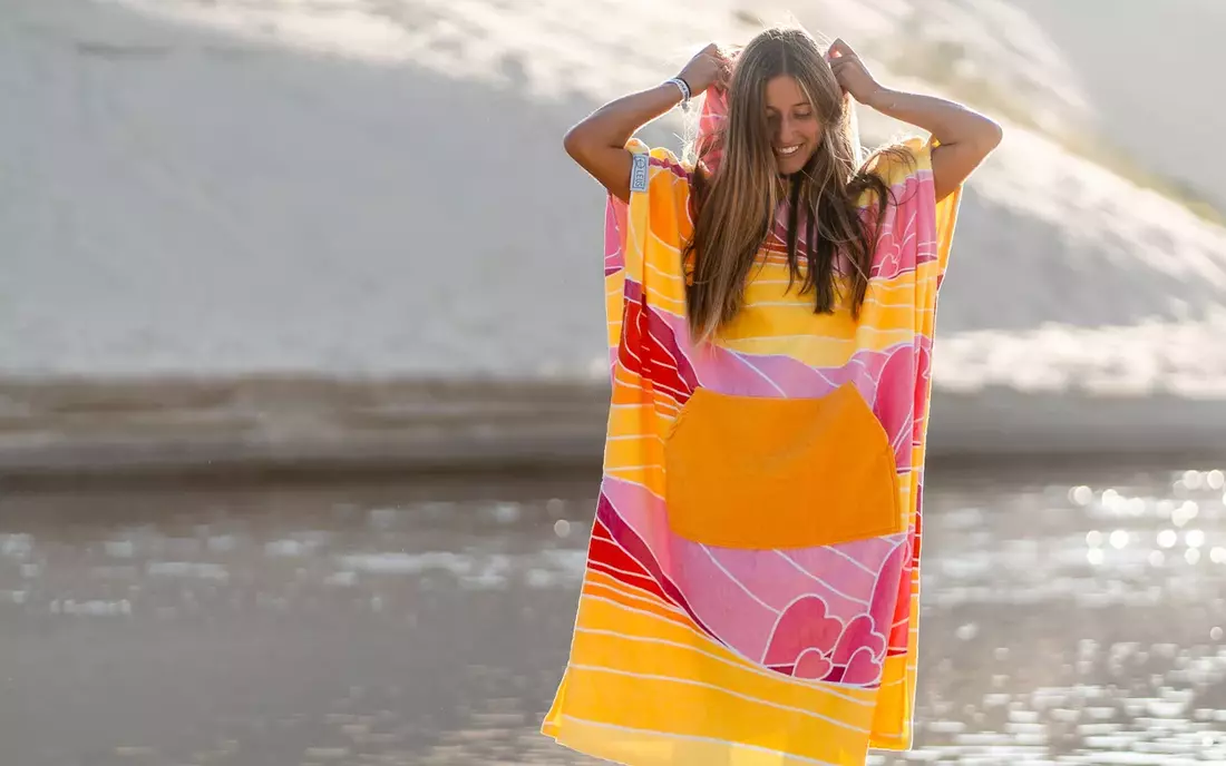 Surferin im Surf Poncho am Strand