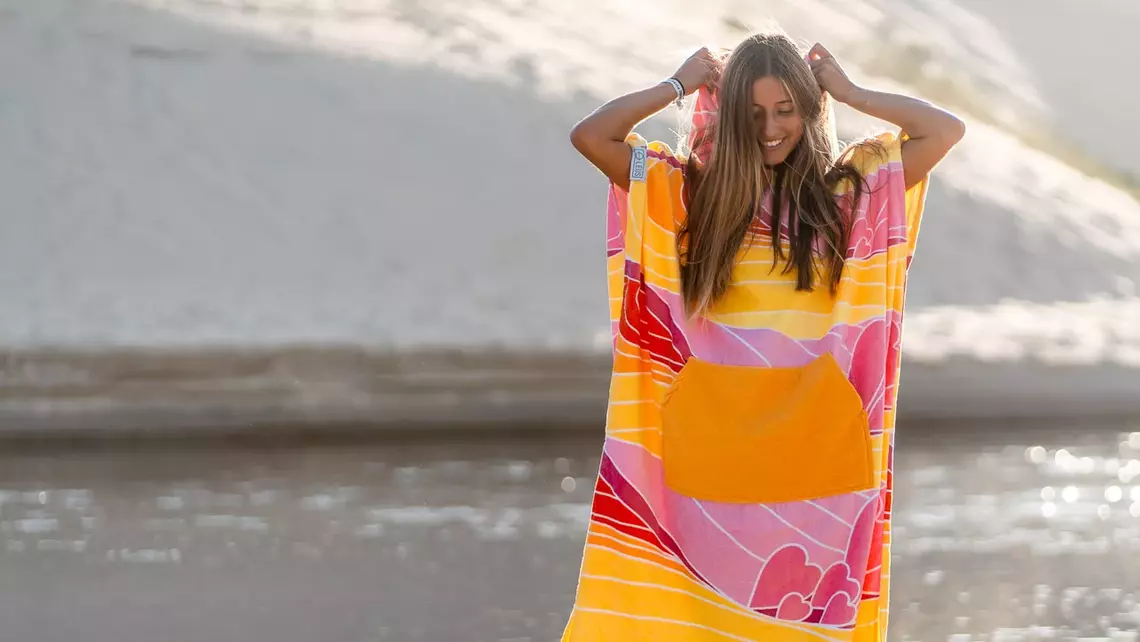 Surferin im Surf Poncho am Strand