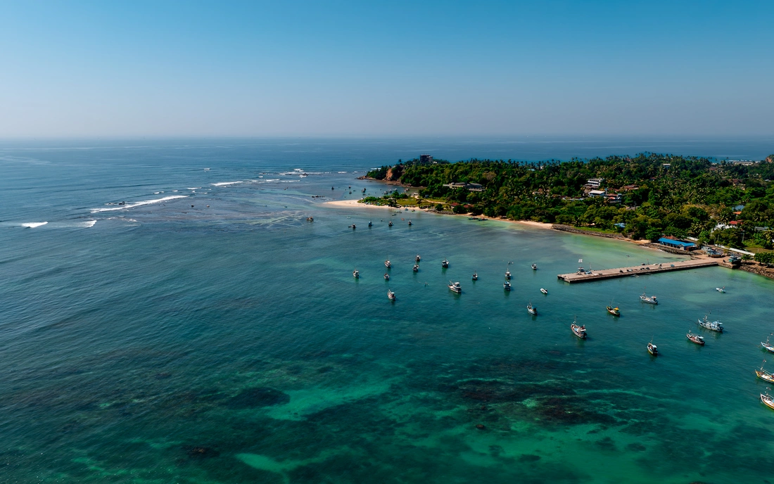 Fishing boats in clear water with reef and waves in Sri Lanka