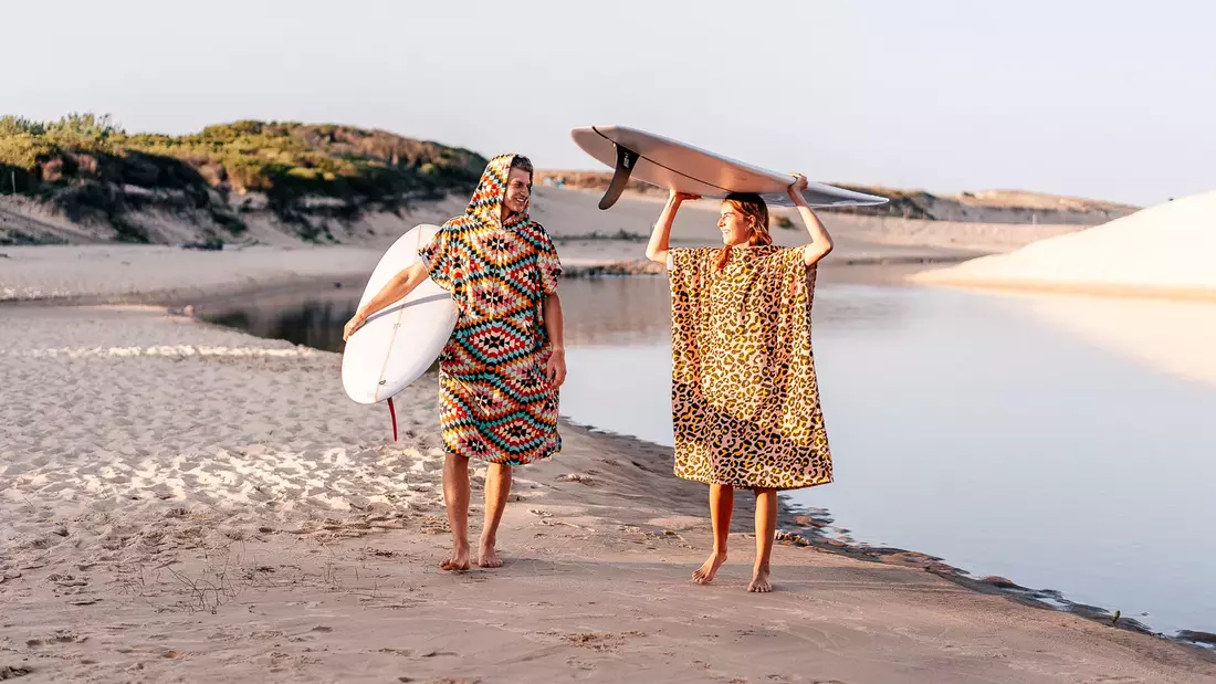 surfer in surfponcho stehen mit surfboard am strand
