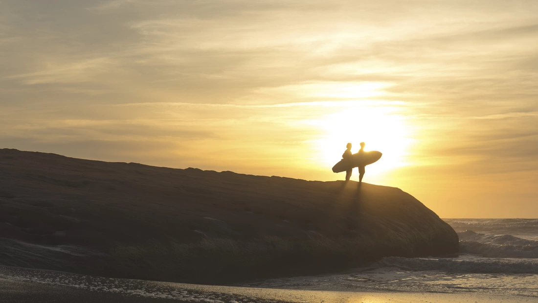 Surfer bei Sonnenuntergang am Strand