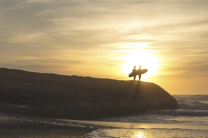 Surfer bei Sonnenuntergang am Strand