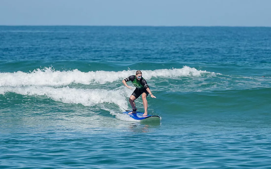 Surferin beim Surfen lernen in einer grünen Welle