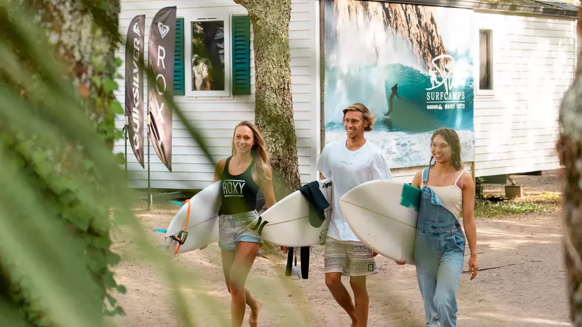 Surfer mit Surfbrett vor Mobile Home im Pure Surfcamp Moliets