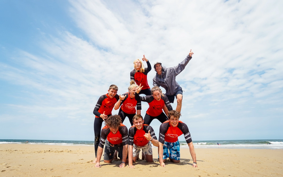 Surfkurs mit Surflehrer beim Gruppenfoto am Strand